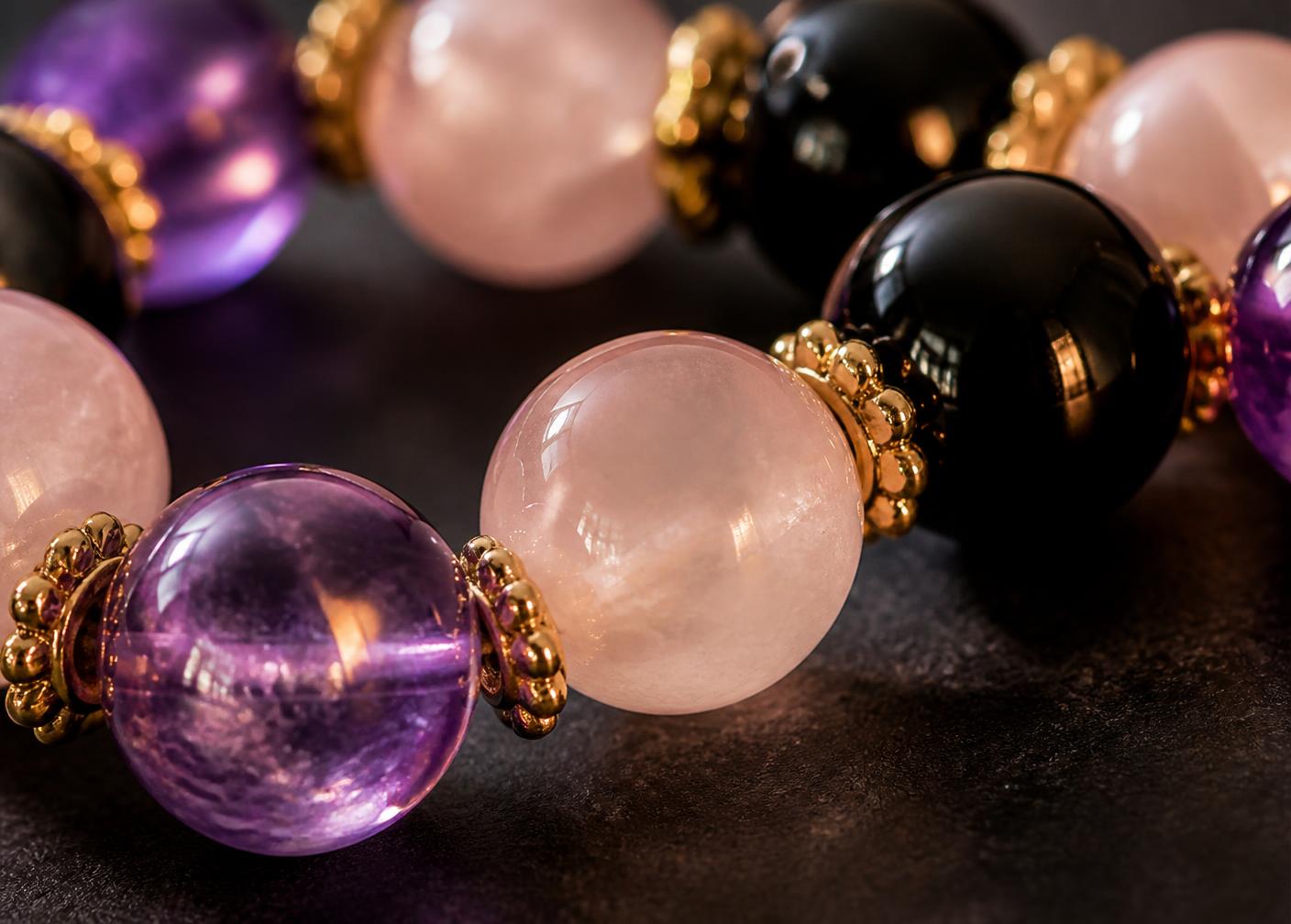 Macro detail of amethyst, rose quartz and black onyx beads with gold spacers